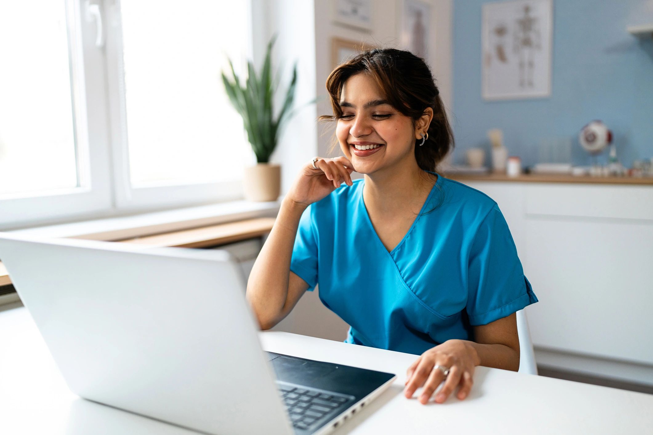 Paramedic learner in scrubs using a laptop for online training